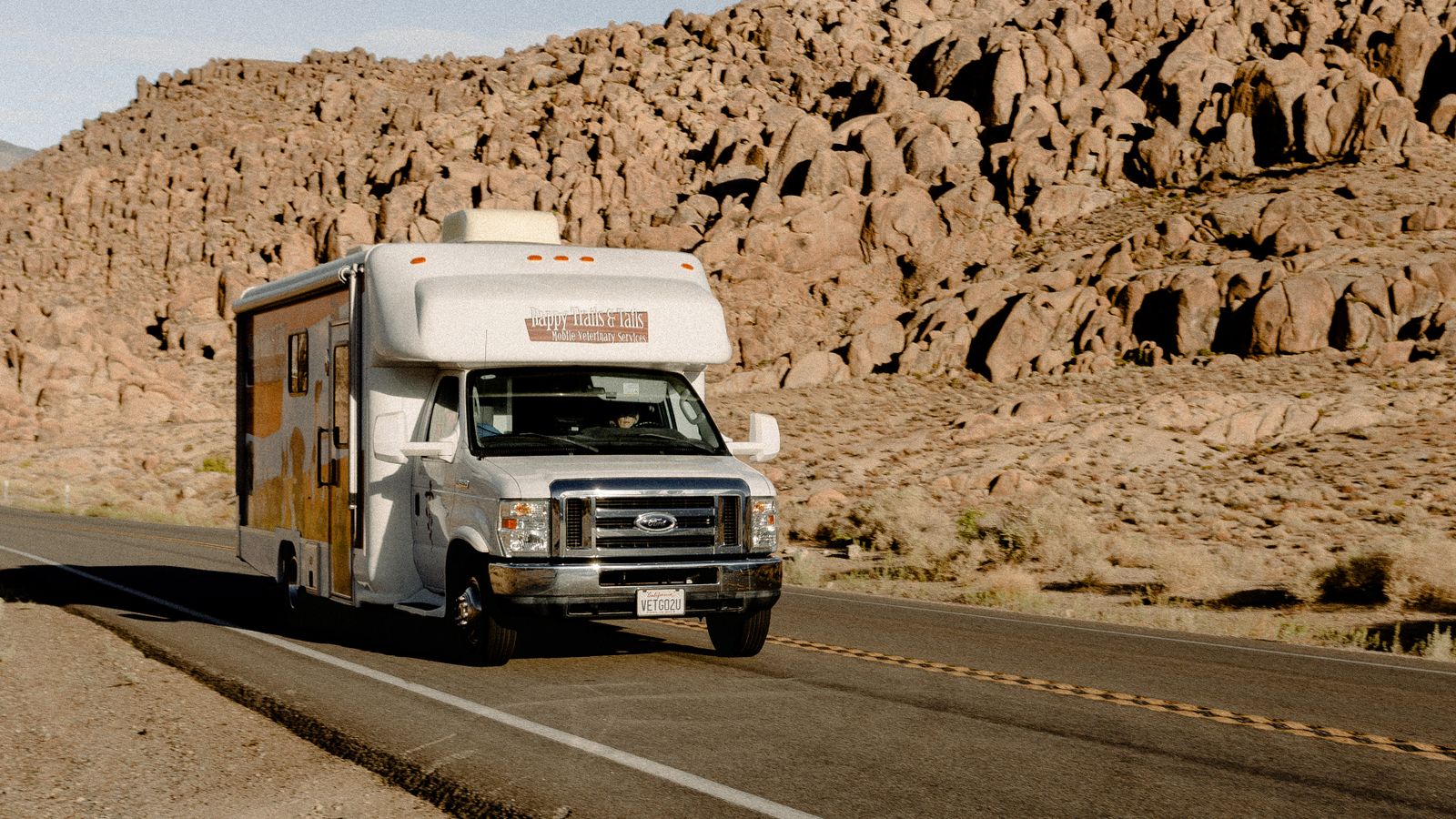 Autocaravana conduciendo por una carretera desértica entre montañas rocosas